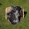 Aquarius Flow woven blanket draped over a chair on grass, highlighting water pouring detail.