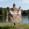 Woman with her back turned, wrapped in the "Best Dad Ever" blanket, showing its size and plaid pattern in orange and beige shades.