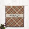 The "Best Dad Ever" blanket hanging on a wall as a decorative tapestry, showcasing its stylish plaid pattern and wording.