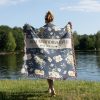 Woman with her back turned, wrapped in the "Best Grandma Ever" blanket, showing its size and gentle floral pattern.