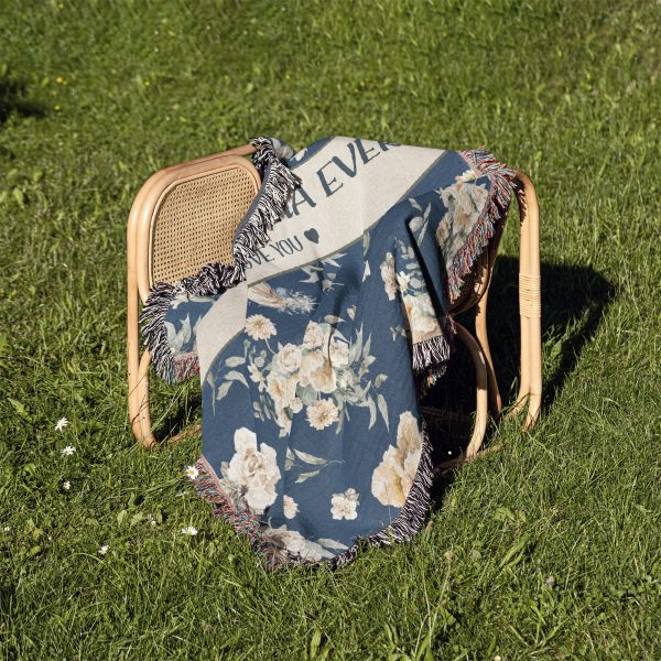 The "Best Grandma Ever" blanket draped over a chair on grass, creating a soft, cozy feel in nature.