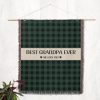 The "Best Grandpa Ever" blanket hanging on a wall as a tapestry, showcasing its plaid pattern and wording.