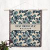 The "Best Mom Ever" blanket hanging on a wall as a tapestry, showcasing its elegant floral design and wording.