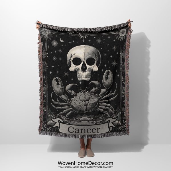 Woman holding the Cancer Spirit woven blanket with crab and human skull design; woman not visible.