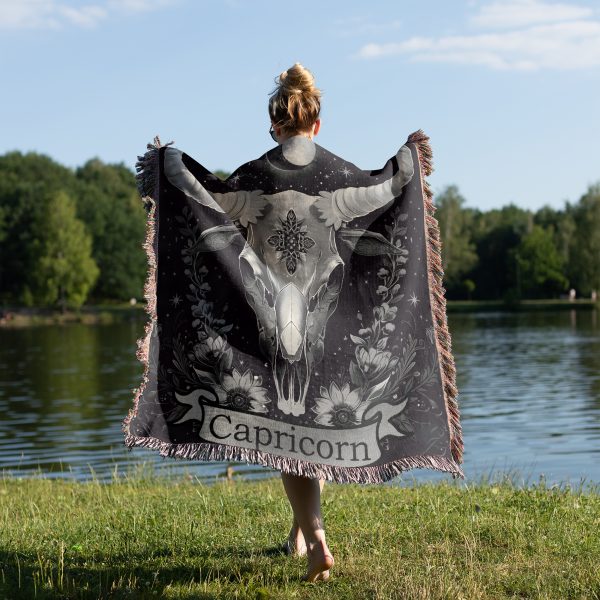 Woman wrapped in Capricorn Resilience woven blanket, goat skull design visible from behind.