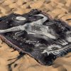 Capricorn Resilience woven blanket with goat skull lying on sandy surface.