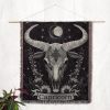 Capricorn Resilience woven blanket hung on wall as tapestry, showcasing goat skull with floral details.