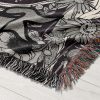 Close-up of Gemini Duality woven blanket, highlighting intricate twin skeletons and floral patterns.