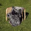 Gemini Duality woven blanket draped over a chair on grass, showing twin skeleton design.