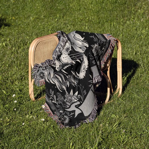 Leo Majesty woven blanket draped over a chair on grass, featuring lion skull design.