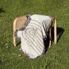 Modern Arc Woven Blanket placed on a chair outdoors on grass, emphasizing its calm and elegant look.