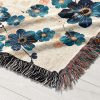 Close-up of Ocean Bloom Woven Blanket, highlighting intricate blue floral details on white background.