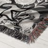 Close-up of Pisces Dream woven blanket, highlighting detailed twin fish skeletons and floral accents.