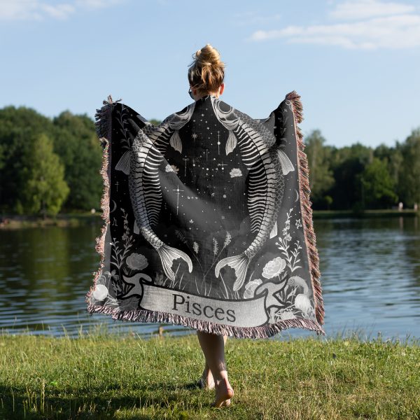 Woman wrapped in Pisces Dream woven blanket, fish skeleton design visible from behind.