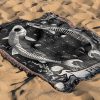 Pisces Dream woven blanket with fish skeletons lying on sandy surface.