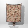 Floral woven blanket held by woman, featuring small, delicate flowers in soft and pastel colors.