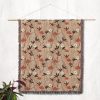 Floral woven blanket hanging on wall as tapestry, featuring tiny, delicate flowers in pastel hues.