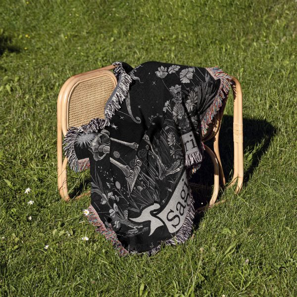 Sagittarius Archer woven blanket draped over a chair on grass, showing archer design.