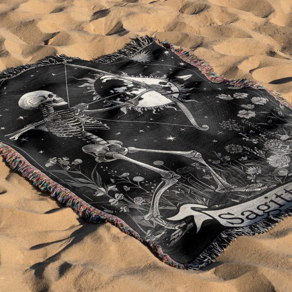 Sagittarius Archer woven blanket with skeleton archer lying on sandy surface.