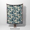 Floral woven blanket held by woman, showcasing delicate flower patterns in soft, romantic colors.