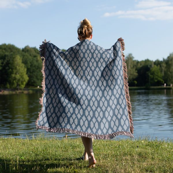 A person wrapped in the Scandinavian Geometric Woven Blanket standing on grass near a lake.