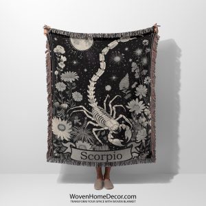 Woman holding the Scorpio Mystery woven blanket with scorpion design; woman not visible.