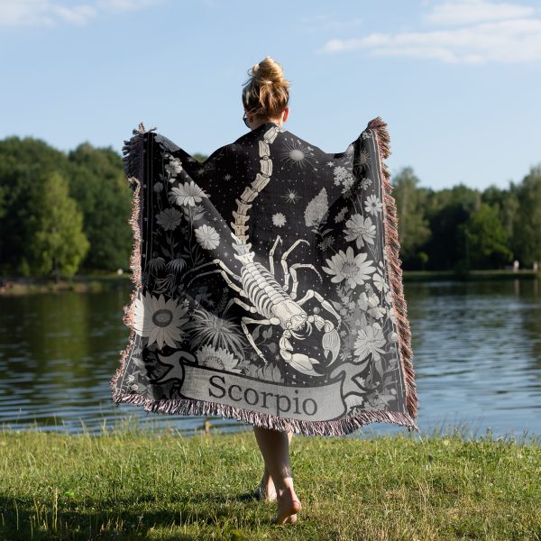 Woman wrapped in Scorpio Mystery woven blanket, scorpion design visible from behind.