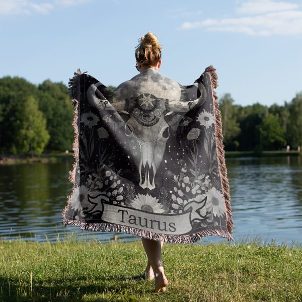 Woman wrapped in Taurus Earth woven blanket, calf skull design visible from behind.