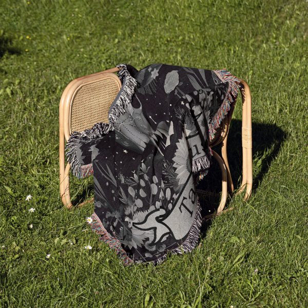 Taurus Earth woven blanket draped over a chair on grass, showcasing calf skull design.