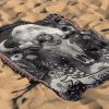 Taurus Earth woven blanket with calf skull and floral pattern lying on sandy surface.