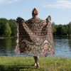 Woman wrapped in Indian style woven blanket, back view, featuring bold traditional design.