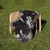 Virgo Grace woven blanket draped over a chair on grass, highlighting skeleton design.