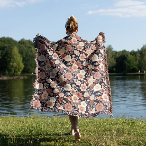 Woman wrapped in floral woven blanket, back view, with vibrant flower patterns in pastel tones.