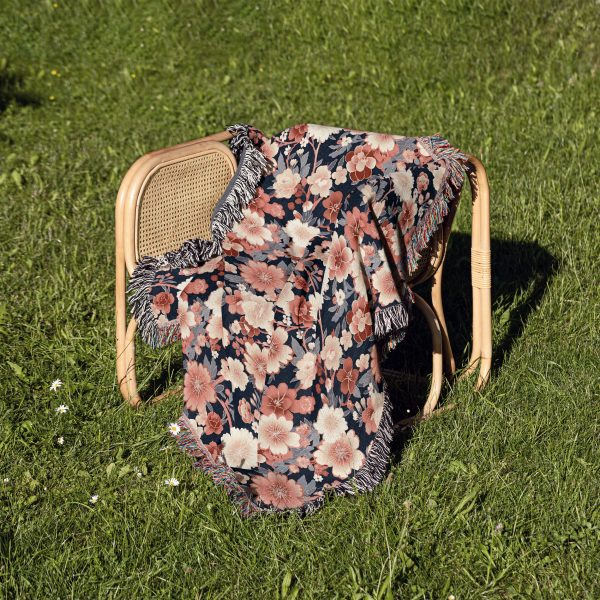 Floral woven blanket on chair, adding a burst of floral colors and delicate patterns to the decor.