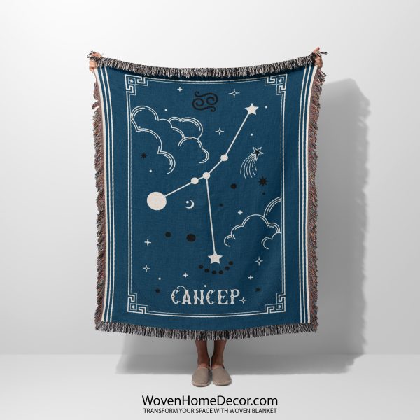 A person holding a Cancer zodiac woven blanket, featuring a detailed crab constellation design with soft blues and delicate celestial accents.