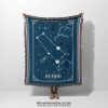 A person holding a Gemini zodiac woven blanket, featuring twin constellation motifs and a soft blue background with delicate star patterns.