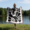 Person standing near a lake, seen from the back, wrapped in the Modern Abstract Woven Blanket.