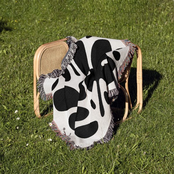 Modern Abstract Woven Blanket placed on a chair outdoors on grass, showcasing its versatility.