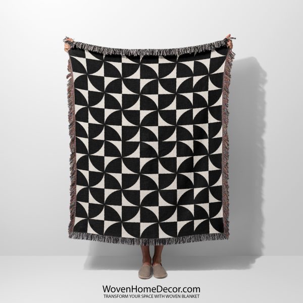 Person holding the Modern Geometric Woven Blanket with bold black-and-white geometric pinwheel patterns.