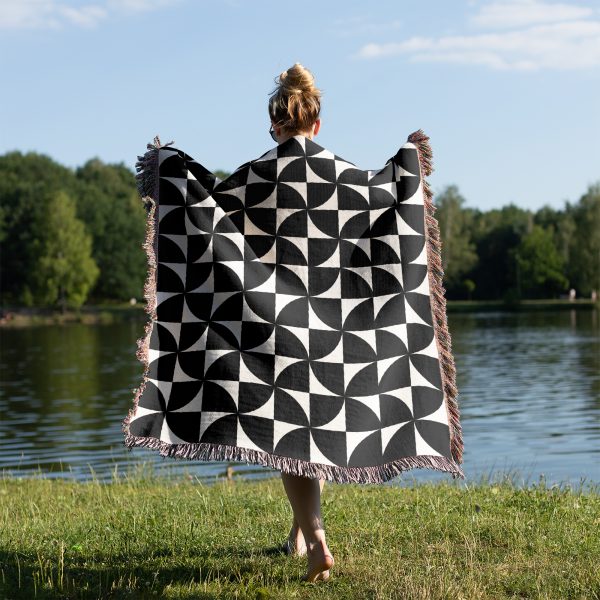 Person standing near a lake, seen from the back, wrapped in the Modern Geometric Woven Blanket.