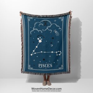 A person holding a Pisces zodiac woven blanket, showcasing a beautiful design of two fish constellations swimming in harmony, with soft blue and turquoise tones.