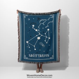 A person holding a Sagittarius zodiac woven blanket, showcasing a vibrant design with the archer constellation in deep purple and gold accents.