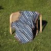 The Scandinavian Striped Woven Blanket neatly folded on a chair outdoors on the grass.