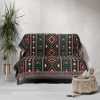 An African-patterned woven blanket styled over a sofa in a rustic interior.