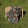 A geometric-patterned woven blanket placed on a chair outdoors on green grass.