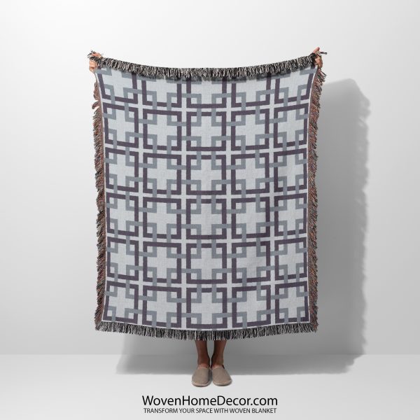 Woman holding a woven blanket with a classic lattice pattern in gray and blue tones, with her face not visible.