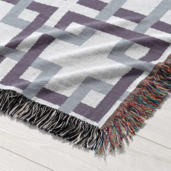 Close-up shot of the woven blanket featuring an elegant lattice pattern in calming gray and blue hues.