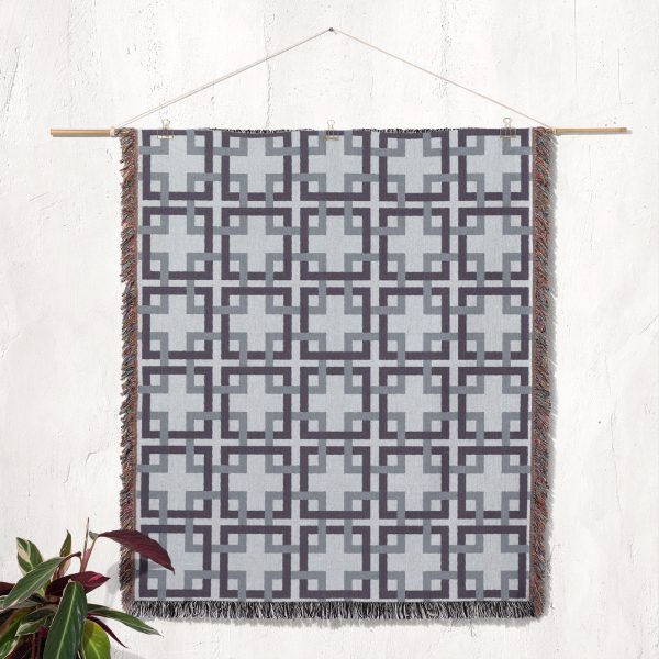 Woven blanket hanging as a tapestry on the wall, showcasing the classic lattice design in gray and blue.