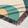 Close-up view of the woven blanket with a bold geometric pattern in terracotta, teal, and mustard.