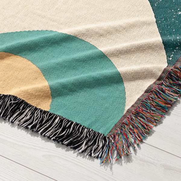 Close-up view of the woven blanket with a bold geometric pattern in terracotta, teal, and mustard.